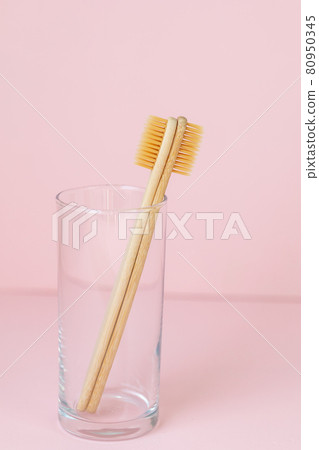 daily human hygiene, cotton swabs and cotton pads, a woman's hand holding bamboo toothbrushes on a pink background in a glass or against a background of plants daily human hygiene, cotton swabs and cotton pads, a woman's hand holding bamboo toothbrushes on a pink background in a glass or against a background of plants 80950345