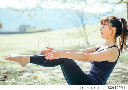Woman doing yoga outdoors (boat pose) 80950964