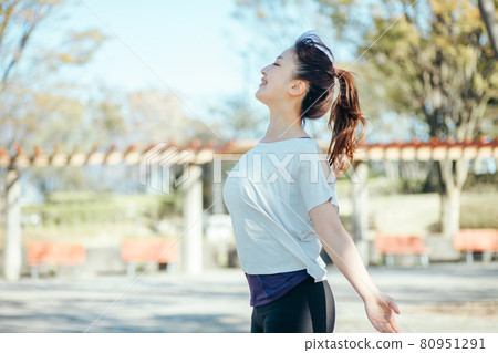 A woman taking a deep breath while playing sports in the park A woman taking a deep breath while playing sports in the park 80951291