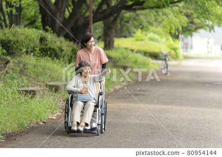 坐在輪椅上的老年婦女和護理人員在公園散步 80954144