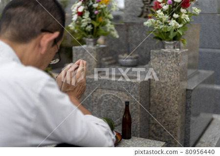 A man visiting a grave and holding hands 80956440