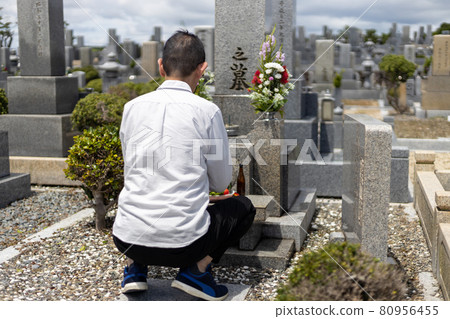 A man visiting a grave and holding hands 80956455