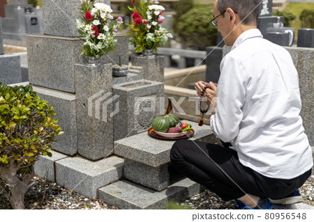 A man visiting a grave and holding hands 80956548