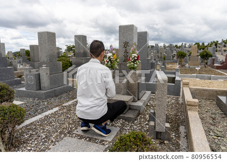 A man visiting a grave and holding hands 80956554
