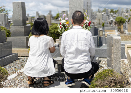 Middle-aged couple visiting a grave and holding hands Middle-aged couple visiting a grave and holding hands 80956618