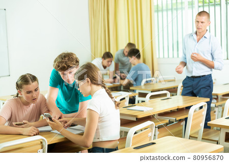 Classmates and teacher working in groups to complete task during class 80956870