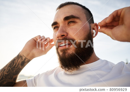 Close up of a man athlete listening to music while having a walk in countryside Close up of a man athlete listening to music while having a walk in countryside 80956929