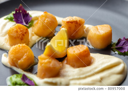 Scallops in creamy sauce on black plate 80957008