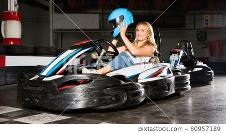 Young woman with helmet sitting in car for karting in sport club Young woman with helmet sitting in car for karting in sport club 80957189