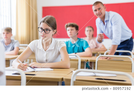 Teen girl listening to lecturer and writing in notebook 80957192