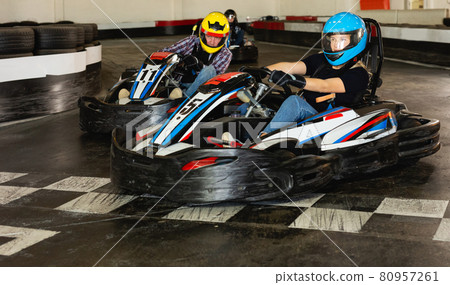 Man and women competing on racing cars Man and women competing on racing cars 80957261