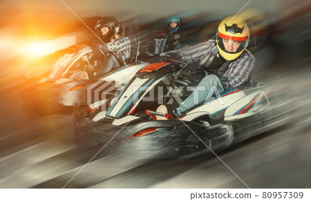 Group of people driving go-carts at racing track Group of people driving go-carts at racing track 80957309