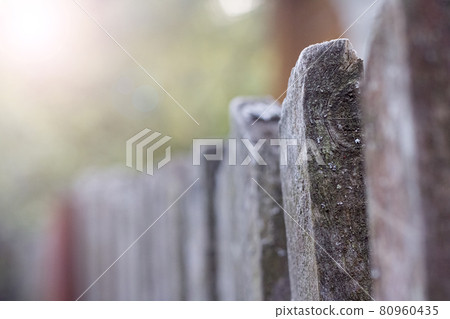 Old wooden rustic fence close up on greenery background Old wooden rustic fence close up on greenery background 80960435