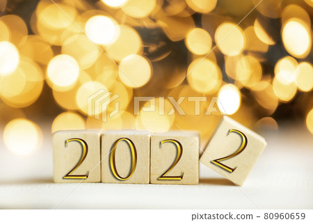 The year 2022 written on wooden cubes in gold luxury letters with shiny bokeh background, New Year celebration concept glitter 80960659