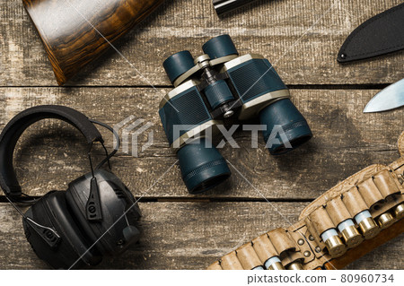 Hunting equipment on old wooden background including rifle, knife, binoculars and cartridges 80960734