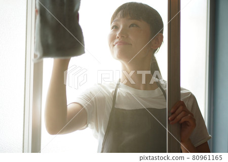 A woman cleaning a screen door 80961165