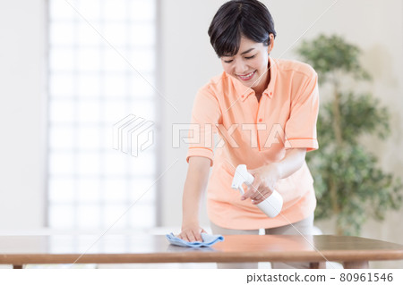 Caregiver wiping the table with disinfectant 80961546