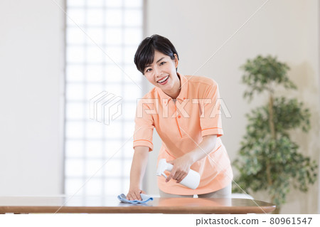 Caregiver wiping the table with disinfectant 80961547