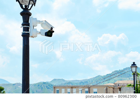 Security camera on a light pole on the street. CCTV surveillance security camera video equipment. Home security system concept. Safety system area control outdoor with copy space, Security camera on a light pole on the street. CCTV surveillance security camera video equipment. Home security system concept. Safety system area control outdoor with copy space, 80962300