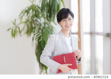Business portrait of a woman standing by the window 80962328