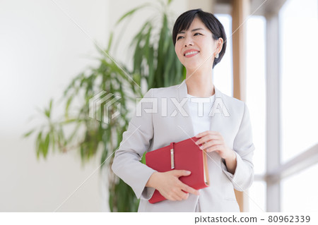 Business portrait of a woman standing by the window 80962339