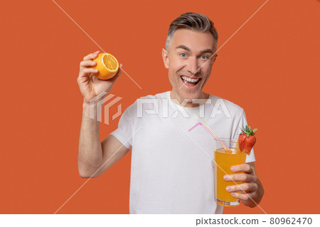 Delighted man with glass of fruit juice 80962470