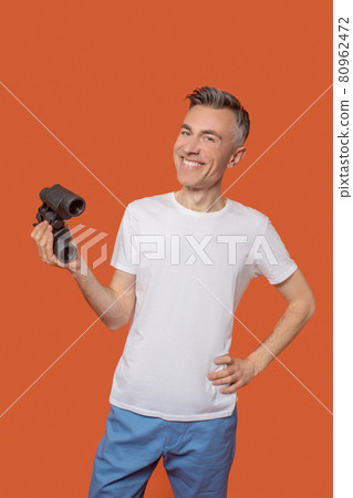 Young adult smiling man standing with binoculars 80962472