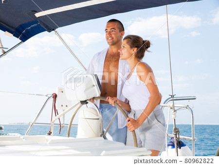 Couple standing at yacht wheel 80962822