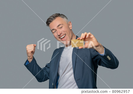 Enthusiastic man with gold bank card 80962957