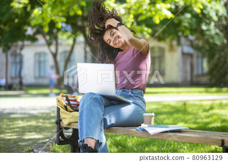 A girl in a pink tshirt with a laptop in the park A girl in a pink tshirt with a laptop in the park 80963129