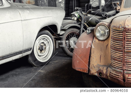 Many rusty abandoned forgotten antique oldtimer old car and motorcycles at junkyard factory storage warehouse indoors. Classic vintage retro vehicles detail garage workshop restore renovation station 80964038