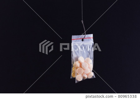 Colored Pills or Tablets Hanging in Small Ziplock Bag on a Fishing Hook Colored Pills or Tablets Hanging in Small Ziplock Bag on a Fishing Hook 80965338