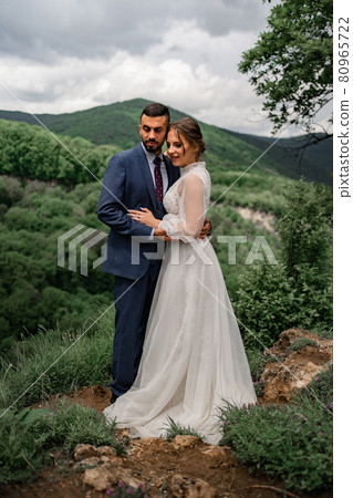a gentle beautiful hugging newlyweds in a wedding ceremony in the mountains 80965722