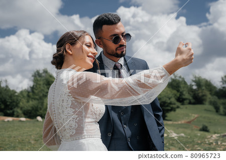 the bride and groom take a selfie together. wedding broadcast online.  80965723