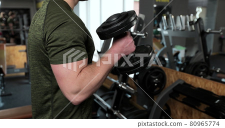 Man doing lift-ups, holding heavy dumbbells in hands, workout for arm muscles. Sportsman doing exercises with weights. Man doing lift-ups, holding heavy dumbbells in hands, workout for arm muscles. Sportsman doing exercises with weights. 80965774