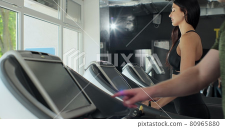 Young athletic man and woman exercising and running on treadmill in sport gym. Active couple training, working out and running on treadmill in fitness gym. Young athletic man and woman exercising and running on treadmill in sport gym. Active couple training, working out and running on treadmill in fitness gym. 80965880