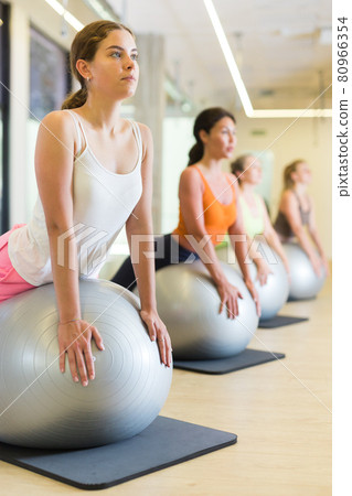 Women during group workout with fitness ball at gym Women during group workout with fitness ball at gym 80966354