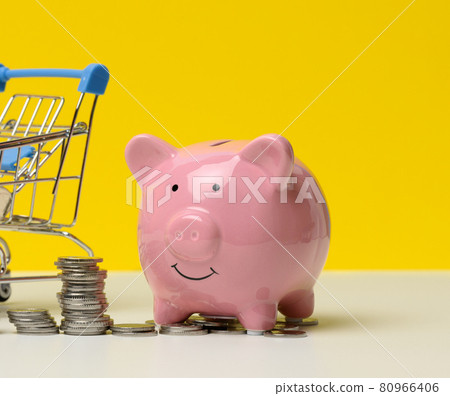 pink ceramic piggy bank and a stack of coins on a white table, yellow background. Savings concept, budget planning. Income growth 80966406