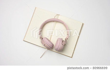 beige wireless headphones and a open notepad on a white background 80966699