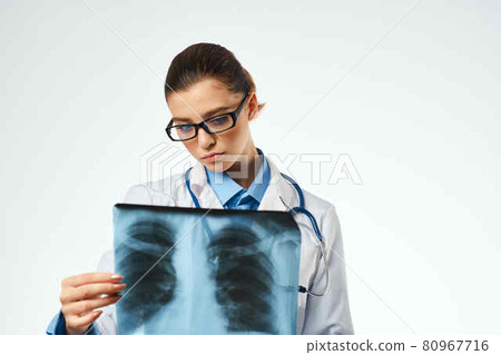 a nurse in a white coat looking at an x-ray Professional examination 80967716