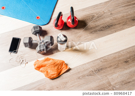 Top view Kettlebells, foar roller, dumbbells, a bottle, a towel and a cell phone 80968417