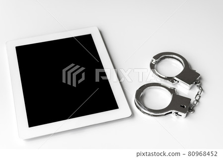 Tablet terminal and handcuffs. Image of cybercrime Tablet terminal and handcuffs. Image of cybercrime 80968452