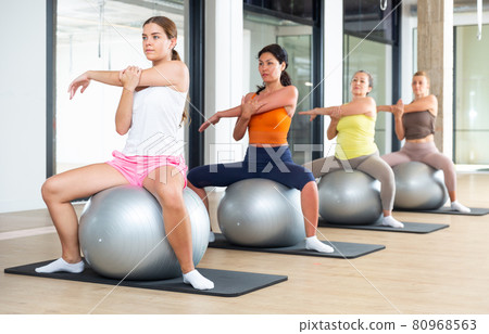 Women sitting on fitness balls in gym Women sitting on fitness balls in gym 80968563