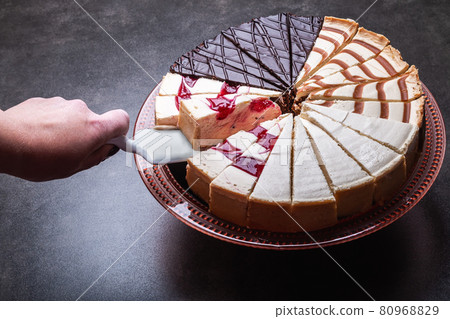 hand with the dessert spatula takes a piece of cheesecake 80968829