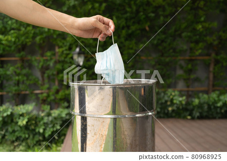 Hand throwing, dumping medical face mask in stainless steel bin. Rubbish, trash, waste or garbage. Outdoor. Environment. Covid-19 or coronavirus outbreak. Hygiene Hand throwing, dumping medical face mask in stainless steel bin. Rubbish, trash, waste or garbage. Outdoor. Environment. Covid-19 or coronavirus outbreak. Hygiene 80968925