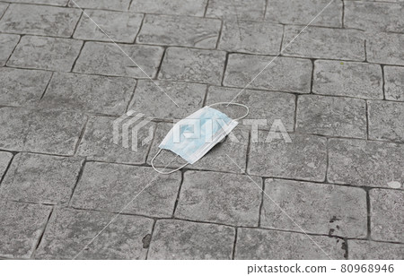 Medical face mask on floor street pavement. Virus protection healthcare item equipment. used. Dirty. Covid-19 or coronavirus pandemic outbreak. 80968946