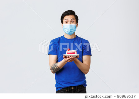 Different emotions, social distancing, self-quarantine on covid-19 and lifestyle concept. Enthusiastic happy guy cant wait eat piece cake, asian male in medical mask holding dessert 80969537