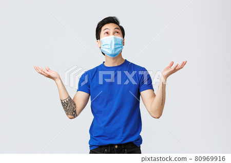 Different emotions, social distancing, self-quarantine on coronavirus and lifestyle concept. Grateful and happy young asian man in medical mask, looking and raising hands up air as raining, falling Different emotions, social distancing, self-quarantine on coronavirus and lifestyle concept. Grateful and happy young asian man in medical mask, looking and raising hands up air as raining, falling 80969916