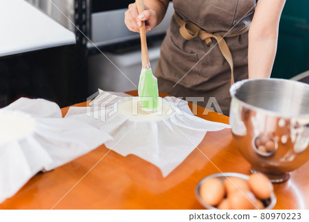 Woman beaker preparing cake mix dough in form for baking tin. indoor 80970223
