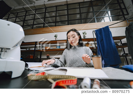 Professional young female tailor working in workshop 80970275